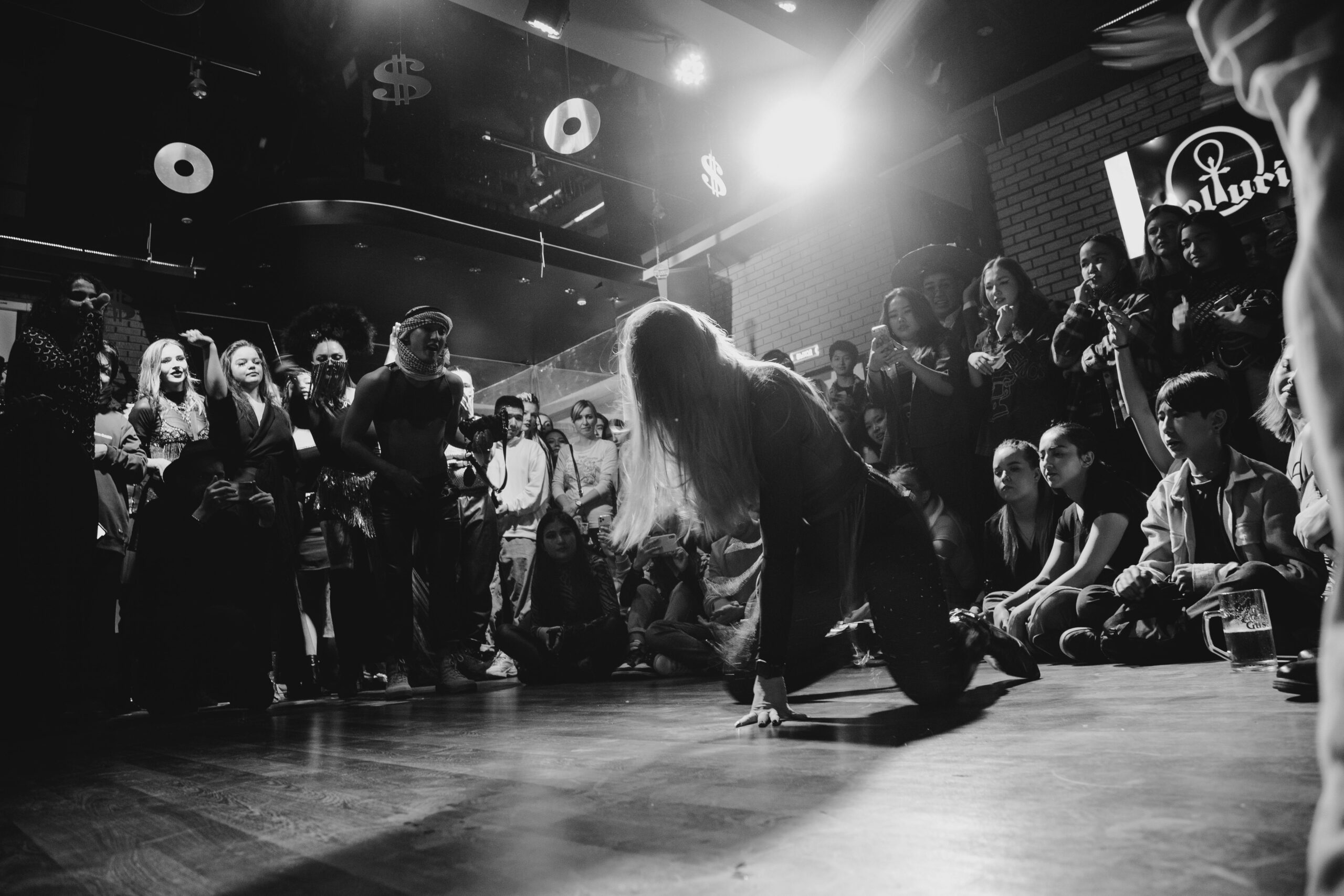 Dynamic black and white shot of a dancer performing to an enthralled crowd in a lively venue.